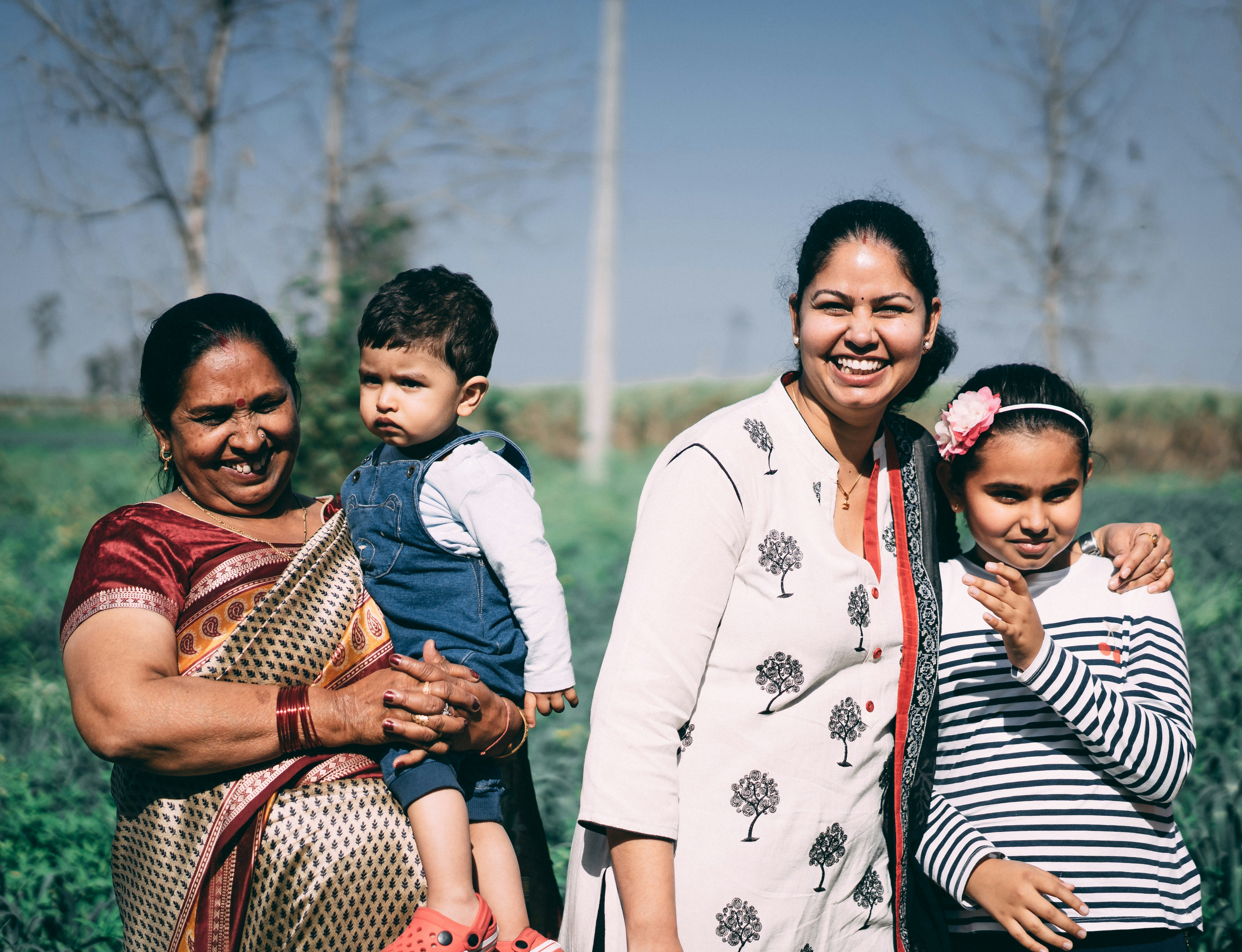 A joyful family stands in a lush field on a sunny day